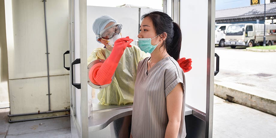 Dr Teo performing the COVID-19 swab test using the booth